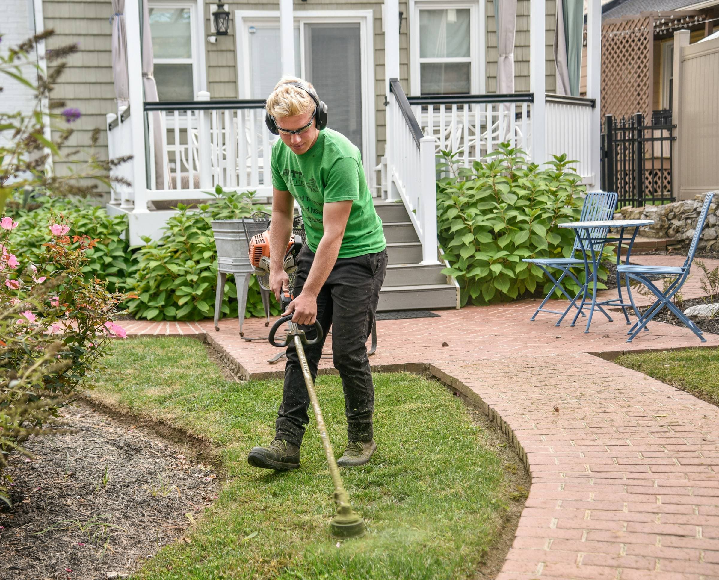 A landscaper trimming the edge of a front yard